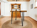 Wooden dining table with black metal legs in a room with wooden flooring and a wooden cabinet.