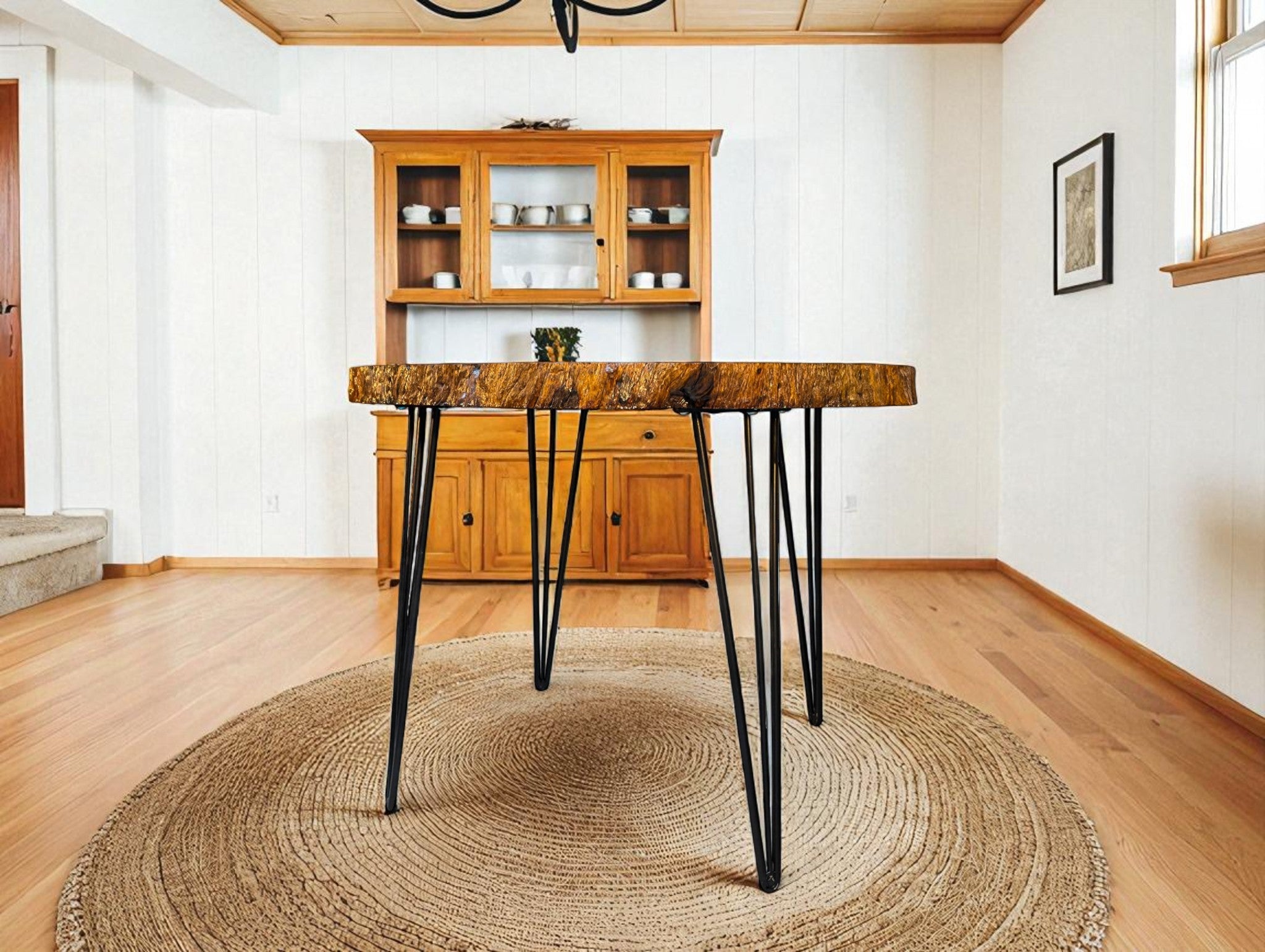 Wooden dining table with black metal legs in a room with wooden flooring and a wooden cabinet.