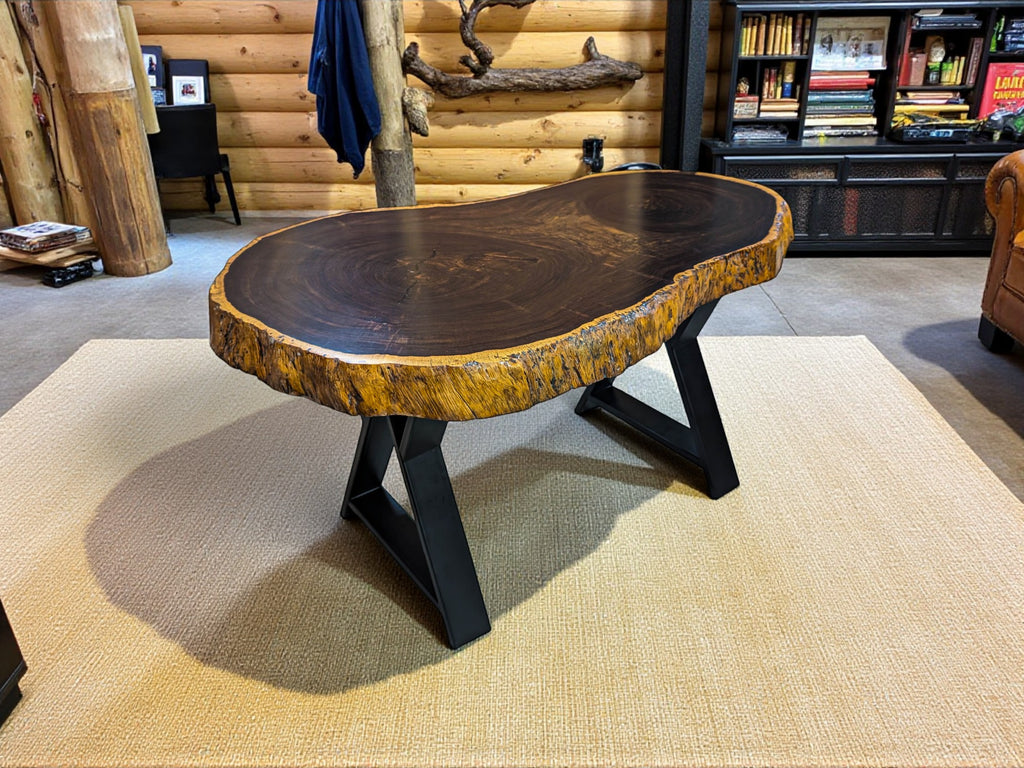 Wooden coffee table with a rustic design in a room with wooden walls and a rug.