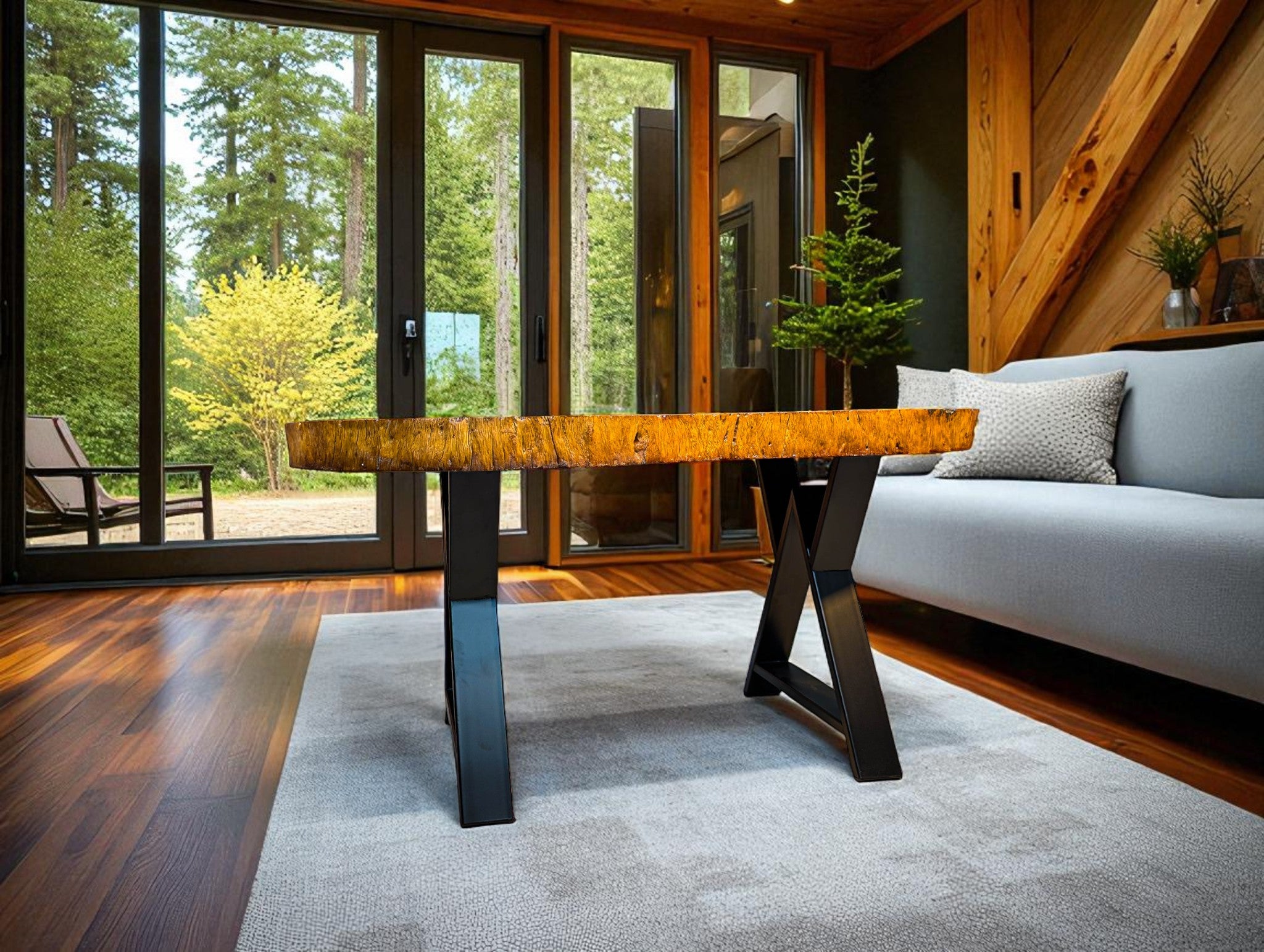 Modern living room with a wooden table, gray sofa, and large windows overlooking trees.