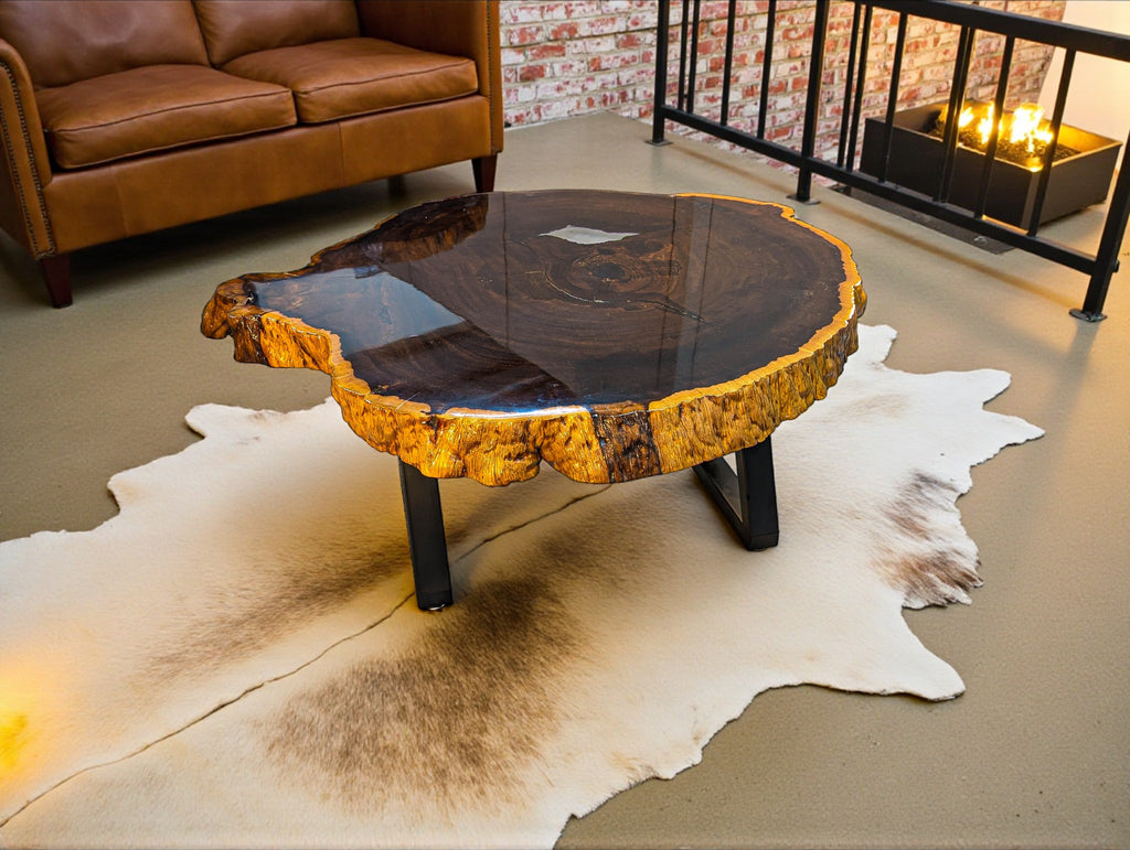 Wooden coffee table with a natural finish on a cowhide rug in a room with a brown sofa and brick wall.