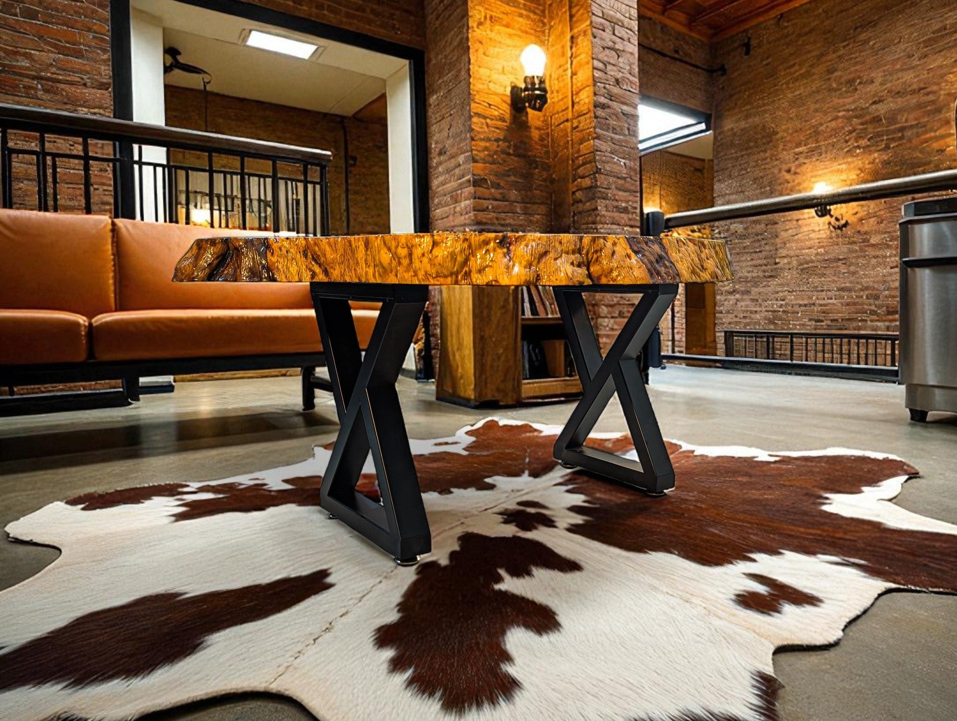 Modern interior with a wooden table on a cowhide rug, leather sofa, and brick walls.