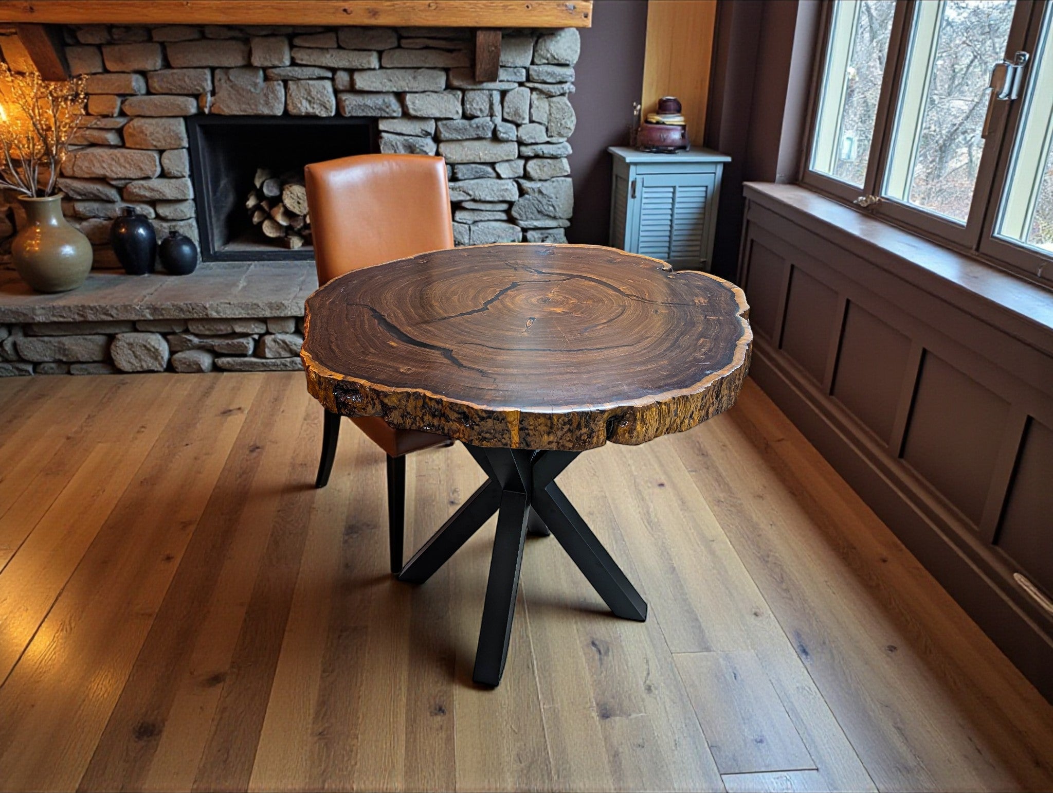 Wooden table with a rustic design in a room with a stone fireplace and wooden floor.